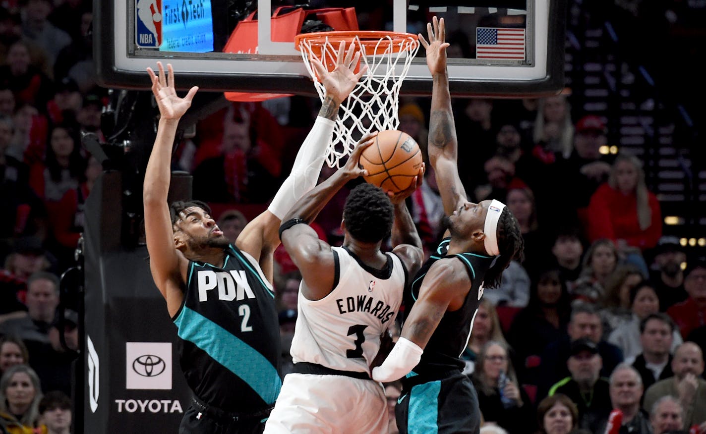 Minnesota Timberwolves guard Anthony Edwards, center, drives to the basket on Portland Trail Blazers forward Trendon Watford, left, and forward Jerami Grant during the second half of an NBA basketball game in Portland, Ore., Saturday, Dec. 10, 2022. The Blazers won 124-118. (AP Photo/Steve Dykes)