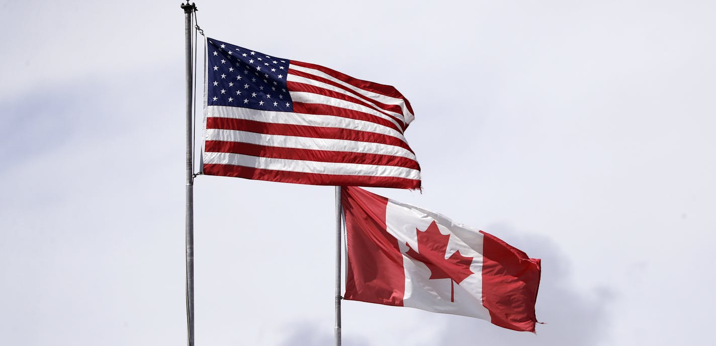 In this photo taken Sunday, May 17, 2020, U.S. and Canadian flags fly atop the Peace Arch at Peace Arch Historical State Park on the border with Canada, where people can walk freely between the two countries at an otherwise closed border, in Blaine, Wash. Canada and the U.S. have agreed to extend their agreement to keep the border closed to non-essential travel to June 21 during the coronavirus pandemic. The restrictions were announced on March 18, were extended in April and now extended by anot