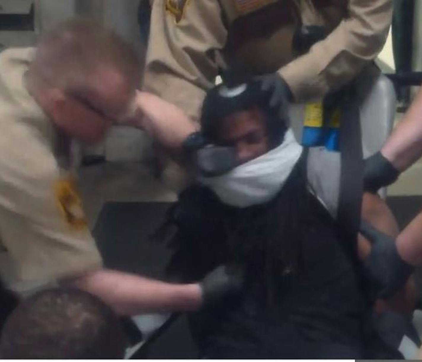 A screenshot from a video shows Correctional Officer Travis VanDeWiele punching Terrell James Johnson as he is brought into the Ramsey County Jail.