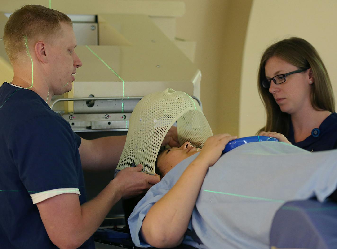 Radiation therapist Charlie Adams, left, and Katie Voigt, adjust patient Ashley Sullivan onto a device for a proton beam therapy, Monday, June 22, 2015 at Mayo Clinic in Rochester, MN. Mayo Clinic is trying to flip the switch and the script on one of the most expensive and controversial innovations in American health care -- proton beam therapy. ] (ELIZABETH FLORES/STAR TRIBUNE) ELIZABETH FLORES &#x2022; eflores@startribune.com