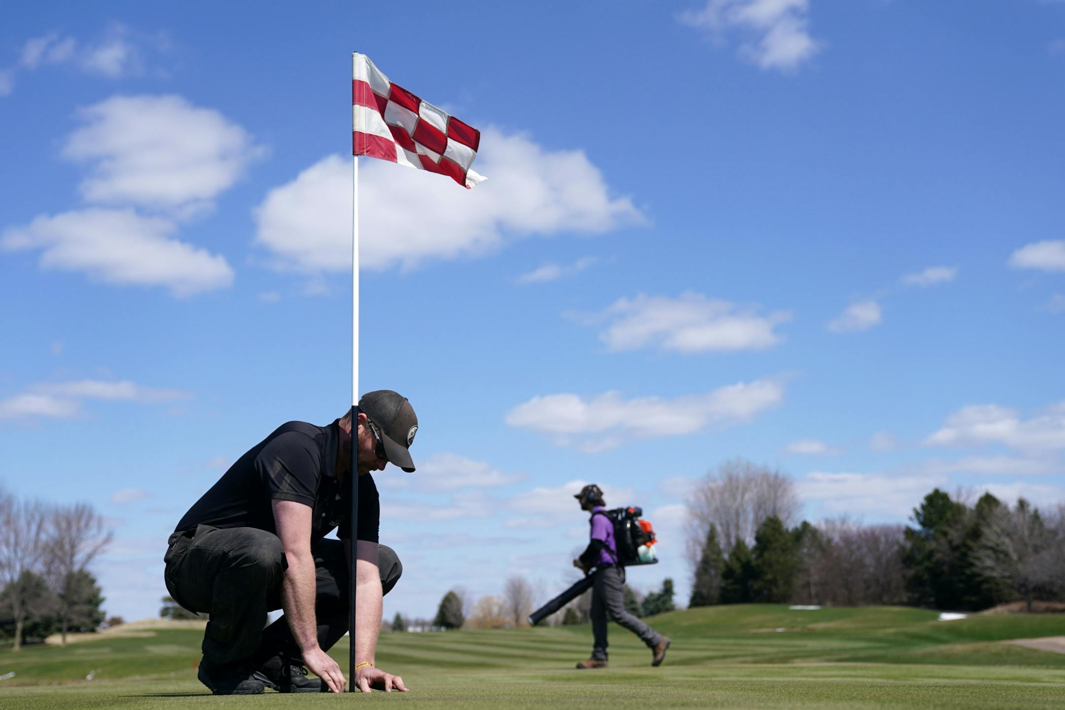 Superintendent Brandon Gauster placed a pin flag for the 10th green, complete with an addition so the ball doesn't fall all the way in the hole, as he and his staff readied the Oak Marsh Golf Course last week.