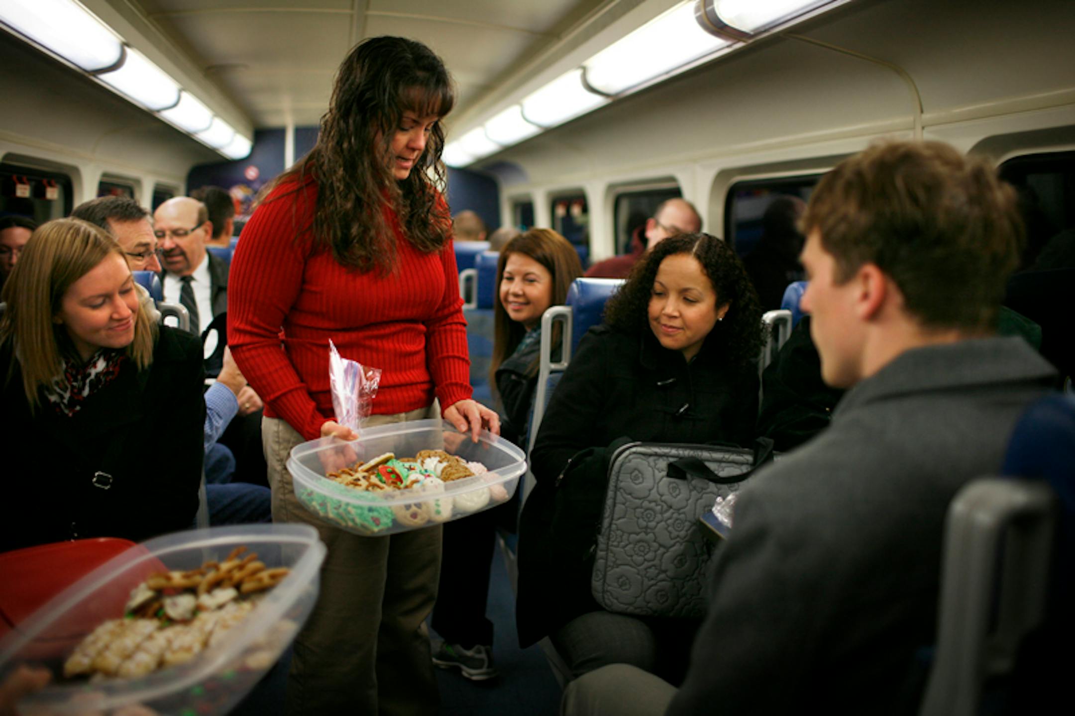 Northstar rider Jill Macdonald, in red, offers Christmas cookies to fellow rider Kendra Randel on the train inbound to Minneapolis. Macdonald had made the cookies and brought them along, part of the holiday festivities of the group of friends who ride the train regularly and who became acquainted on the train.