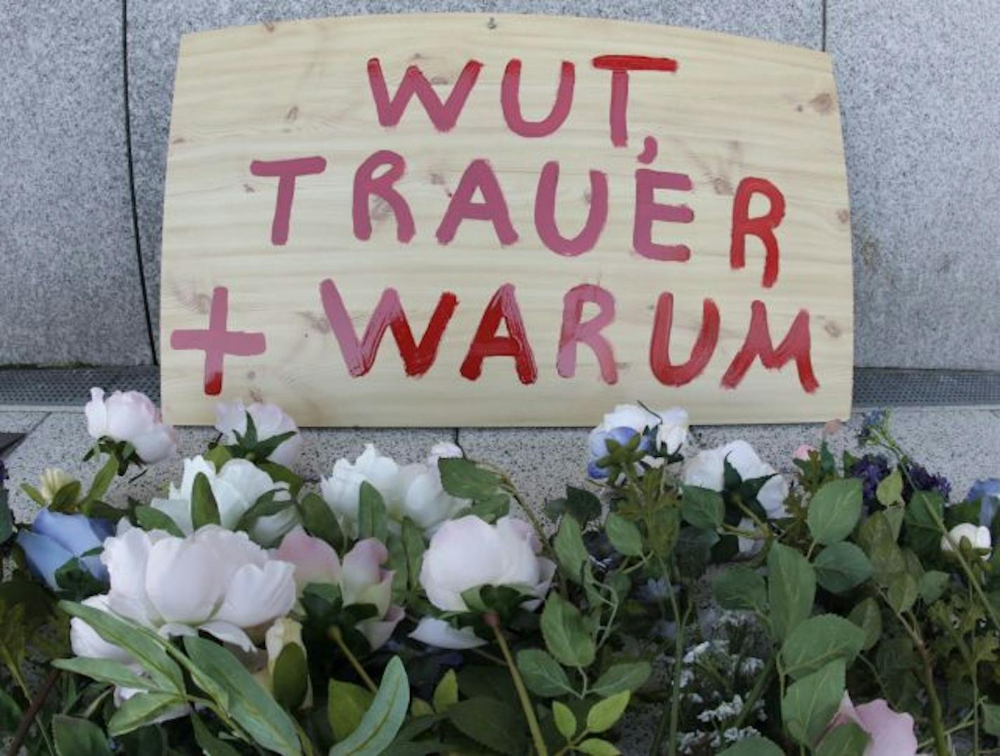 Flowers and a sign that translates as "anger, grief, why" were left at the Frankfurt airport, where American airmen were attacked.