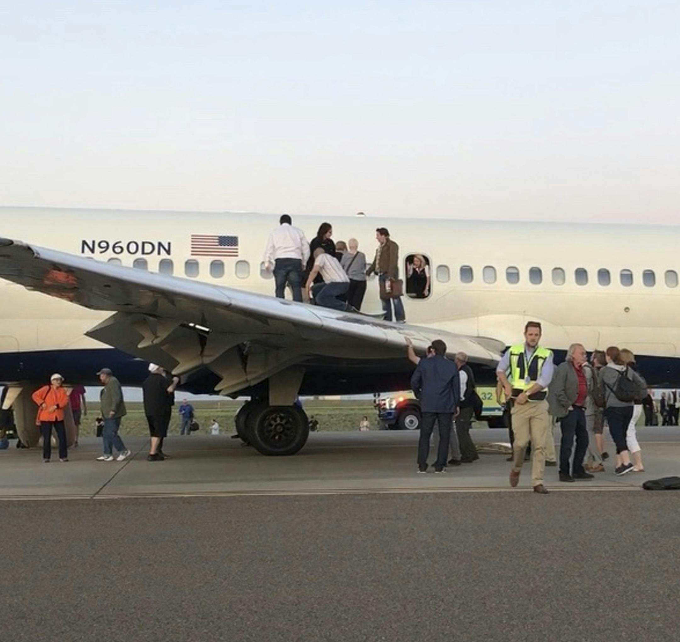Passengers exit a plane and stand on the tarmac of Denver International Airport after being evacuated from a Delta flight from Detroit on Tuesday May 8, 2018, in Denver. A Delta Air Lines flight with 153 people on board was evacuated at Denver's airport after passengers reported smoke in the cabin. (Rachel Naftel via AP)
