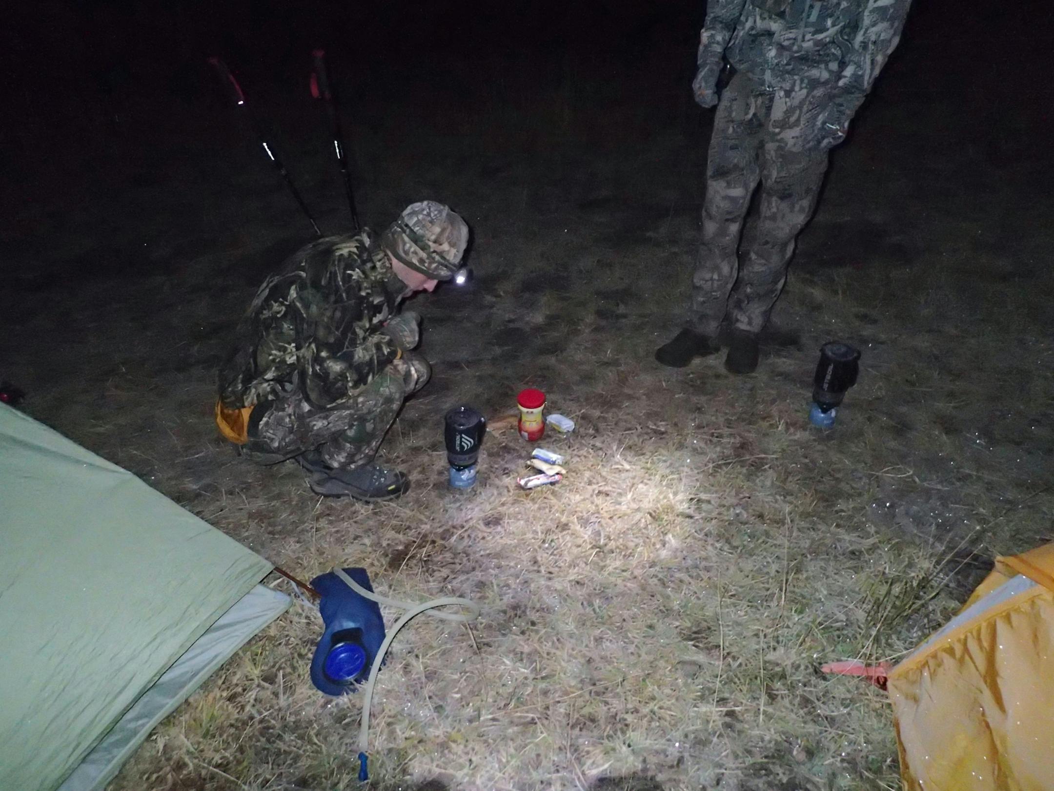 Dennis Anderson, his son Trevor, 23, and Alec Underwood, also 23, the latter two of Missoula, Mt., hiked into the Montana mountains to hunt elk by archery. To hide their presence, and lighten their backpacks, they built no campfires and ate only energy bars for breakfast and lunch. Dinner was dehydrated food. Here Underwood, kneeling, watches a jet boil burner heat water for morning coffee.