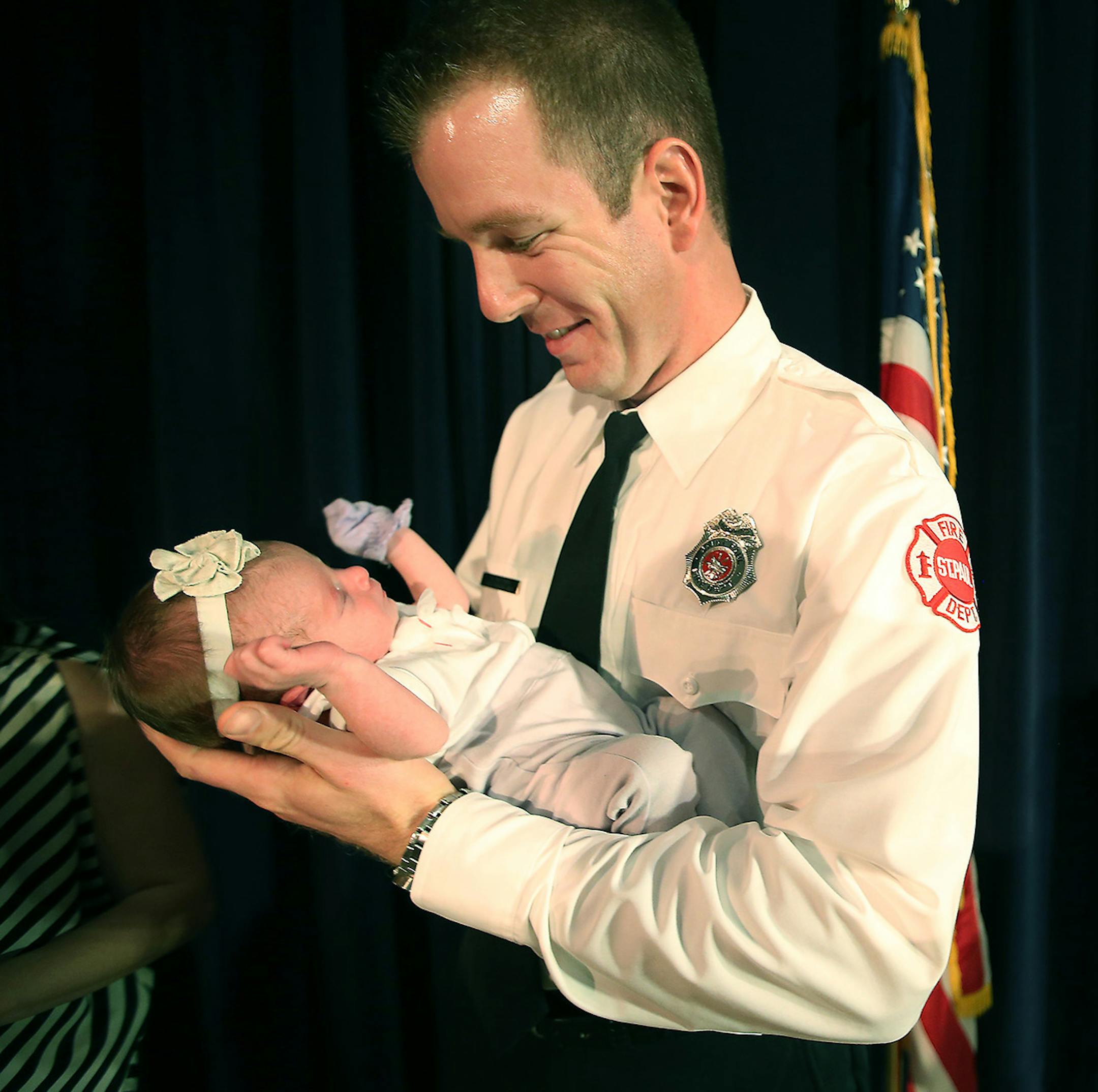 New St. Paul Firefighter, Joel Waters held his 10-day-old baby Sofia after his wife placed his bade on him at the St. Paul Firefighter Graduation at St. Paul College, Friday, September 19, 2014 in St. Paul, MN. ] (ELIZABETH FLORES/STAR TRIBUNE) ELIZABETH FLORES • eflores@startribune.com