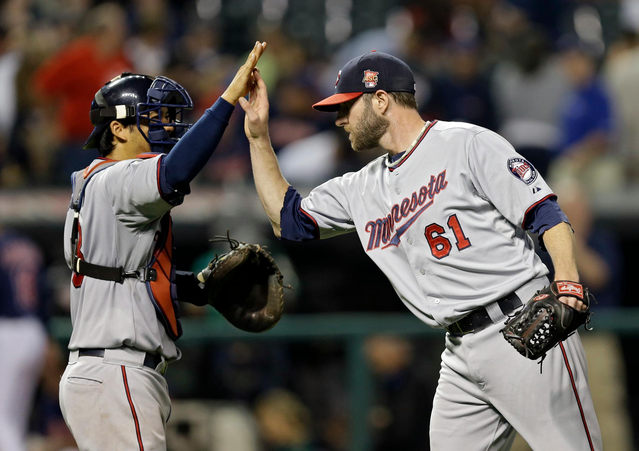 Minnesota Twins relief pitcher Jared Burton (61) celebrates with catcher Kurt Suzuki after a 4-3 win over the Cleveland Indians in a baseball game Tuesday, Sept. 9, 2014, in Cleveland. (AP Photo/Mark Duncan)