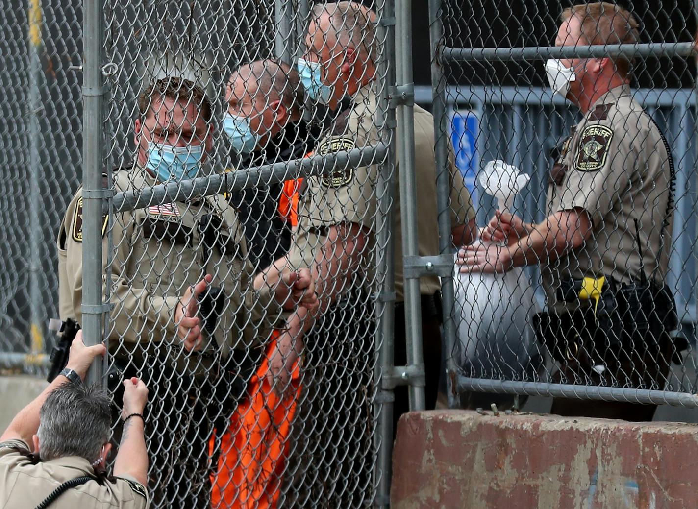 A law enforcement officer goes down while opening a gate for fired Minneapolis police officer Derek Chauvin, being escorted from the Family Justice Center after a hearing Friday in Minneapolis.