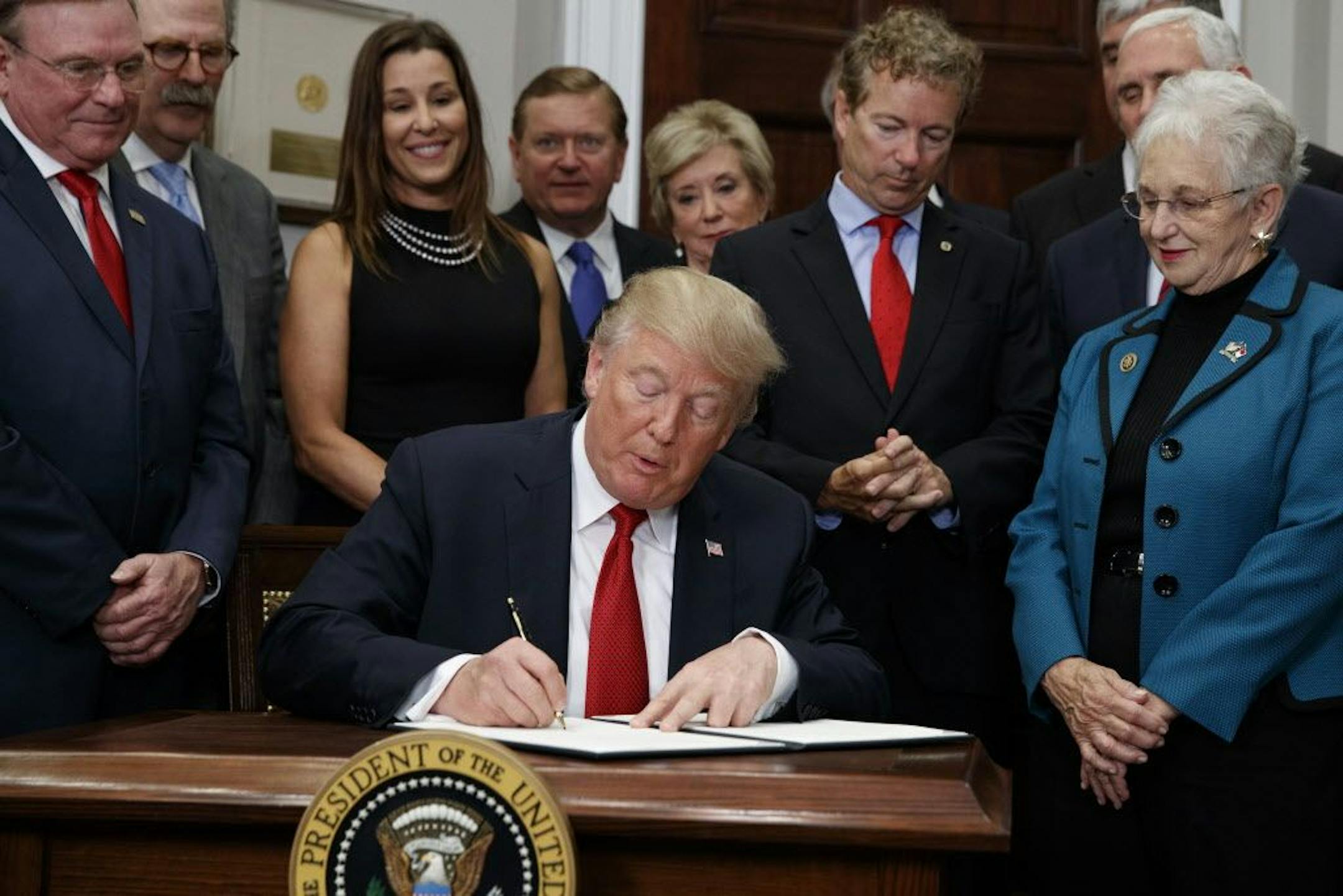 President Donald Trump signs an executive order on health care in the Roosevelt Room of the White House, Thursday, Oct. 12, 2017, in Washington.