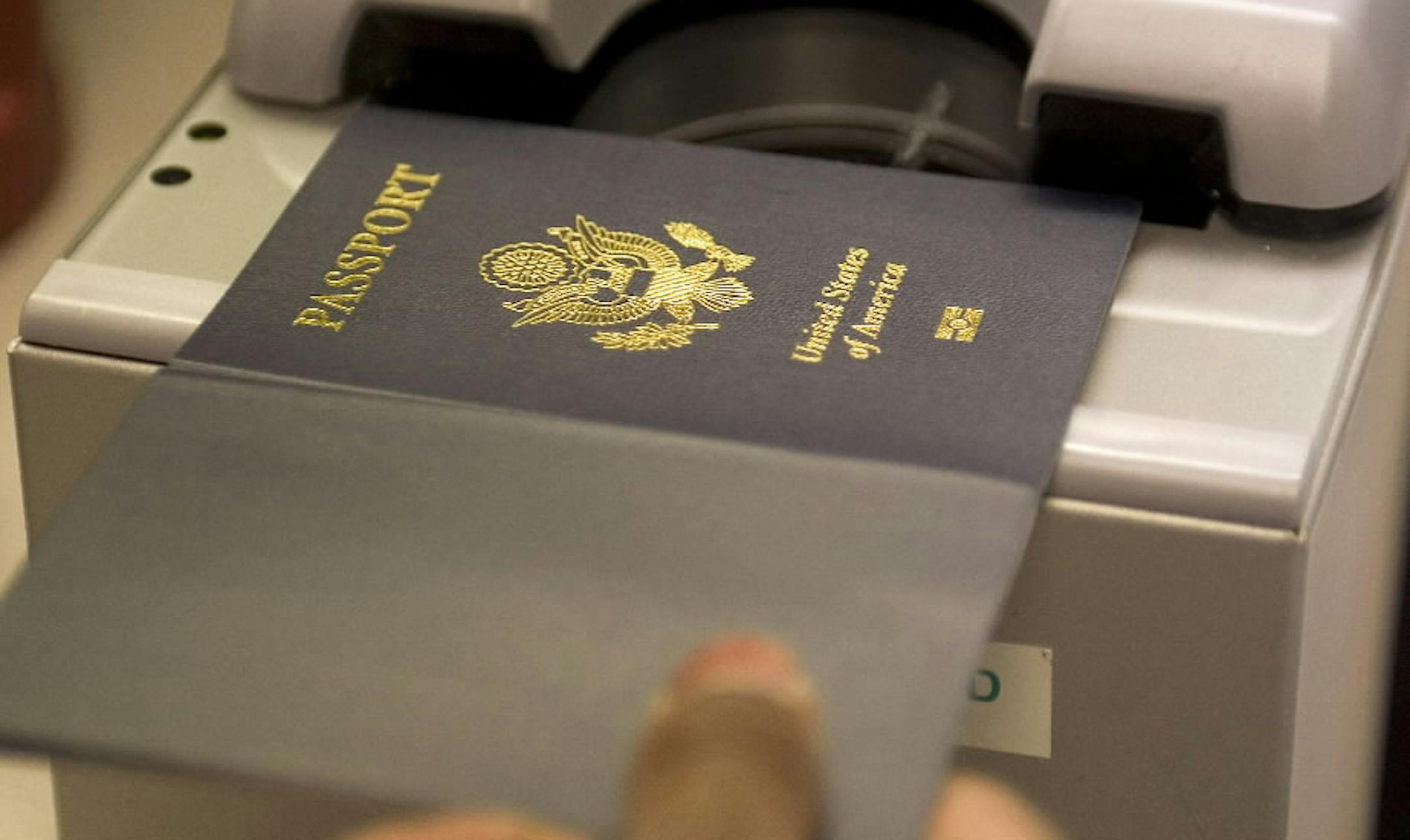 A US government official with the State Department's Passport Services enters a new "electronic passport" with an embedded small integrated chip into a reader for processing personal data and the photograph of an applicant.