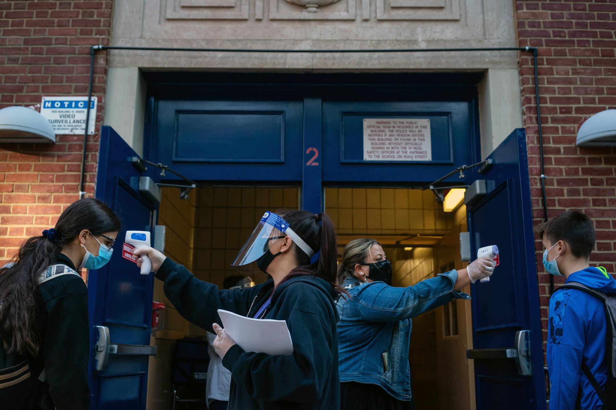 FILE -- Students have their temperature checked as they arrive at Junior High School 157 in Queens on Oct. 1, 2020. Nearly three weeks into the in-person school year, early data from the city's first effort at targeted coronavirus testing has shown a surprisingly small number of positive cases. (Todd Heisler/The New York Times)