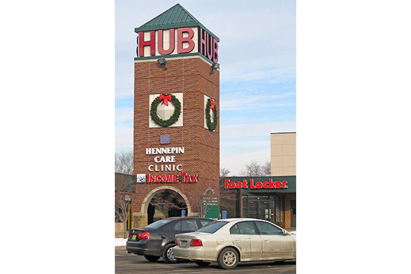 Brick spire of Hub decorated for Christmas with a wreath and cars parked in front.