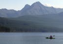 FILE - In this Sept. 6, 2013, file photo, a woman kayaks on Kintla Lake in Glacier National Park, Mont. A grizzly bear attacked and killed a 38-year-o