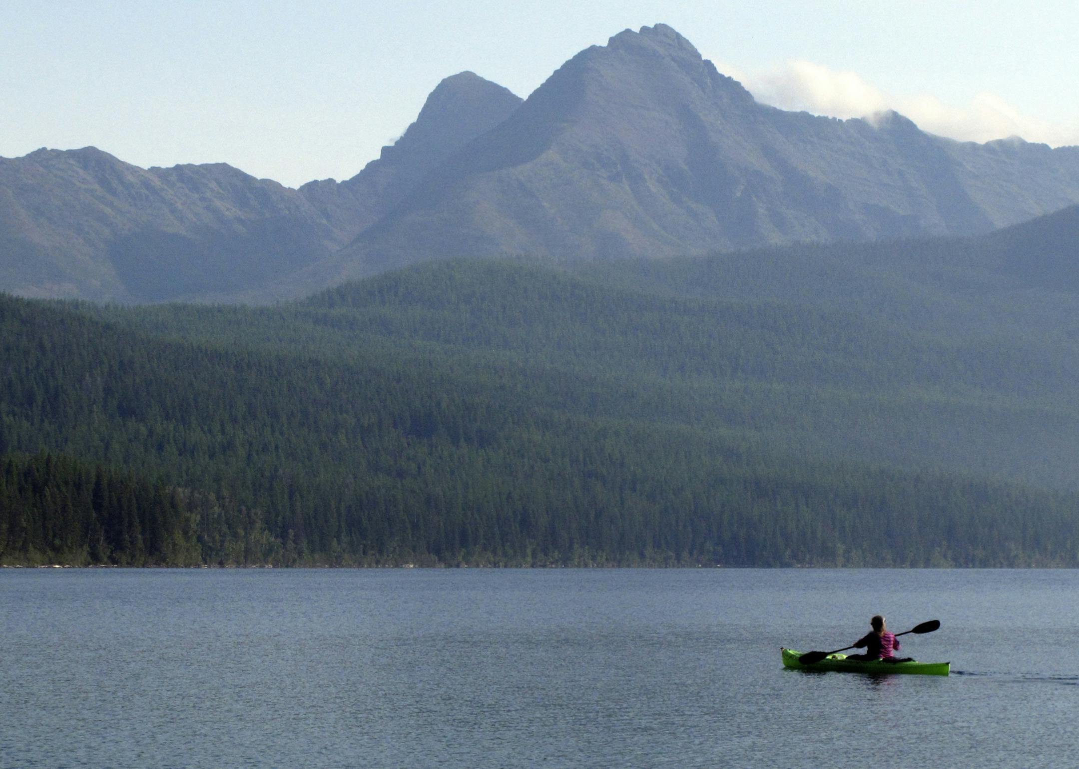 FILE - In this Sept. 6, 2013, file photo, a woman kayaks on Kintla Lake in Glacier National Park, Mont. A grizzly bear attacked and killed a 38-year-old mountain biker Wednesday, June 29, 2016, as he was riding along a trail just outside the national park, Montana authorities said. (AP Photo/Matt Volz, File) ORG XMIT: NY132