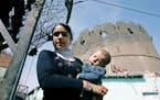 ** FILE ** In this March 20, 2008 file photo, a young woman holds a baby outside historical walls surrounding city center of southeastern Turkish city