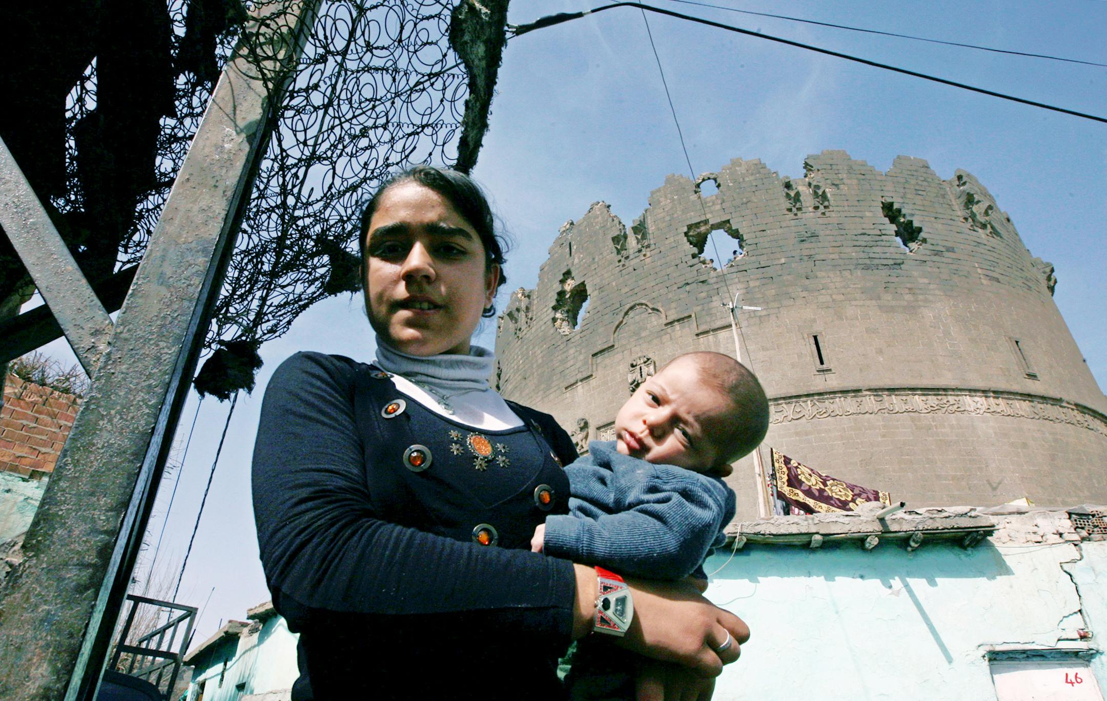 ** FILE ** In this March 20, 2008 file photo, a young woman holds a baby outside historical walls surrounding city center of southeastern Turkish city of Diyarbakir. Kurdish politicians boycotted a major speech by Turkey's prime minister Tayyip Erdogan in Diyarbakir, Tuesday, May 27, 2008, to protest what they say is the government's refusal to recognize the country's Kurdish minority. Erdogan gave details of plans he first unveiled in March for economic and cultural initiatives for the region.(