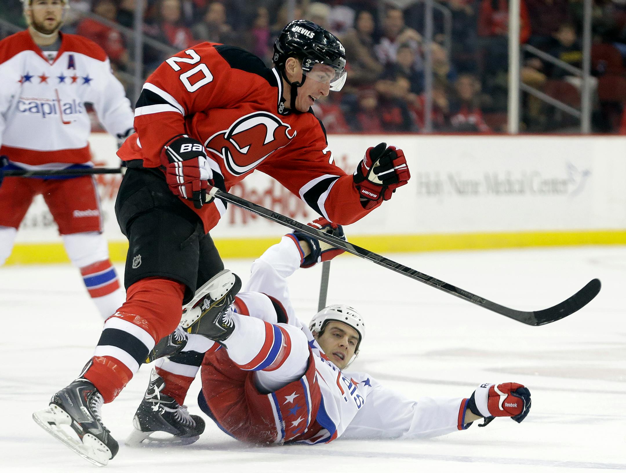 Washington Capitals left wing Aaron Volpatti, bottom, is leveled by New Jersey Devils center Ryan Carter during the first period of an NHL hockey game, Friday, Jan. 24, 2014, in Newark, N.J. (AP Photo/Julio Cortez)