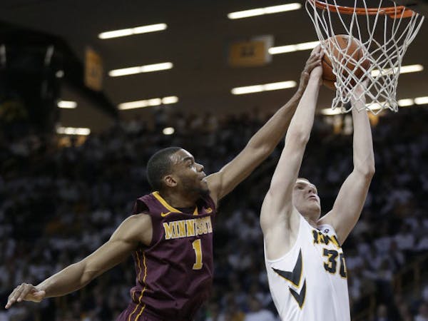 Iowa forward Aaron White, right, drives to the basket past Minnesota guard Andre Hollins during the first half Thursday in Iowa City.