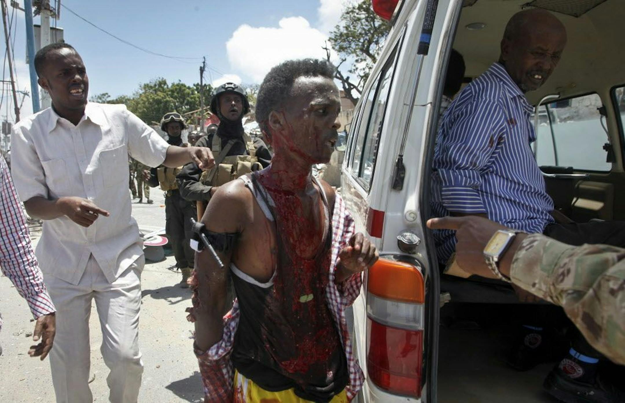 A man who was wounded by a blast near the presidential palace is helped into a vehicle in the capital Mogadishu, Somalia Tuesday, Aug. 30, 2016. A suicide bomber has detonated an explosives-laden truck near the gate of Somalia's presidential palace in the capital on Tuesday, killing at least five people, police say.