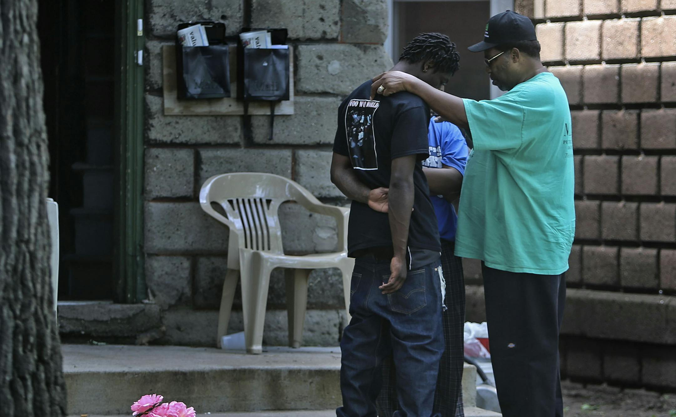 VJ Smith of Mad Dads prays over two young adults at the scene of an early morning shooting that left one female dead and another wounded on 3rd St. N, near 26th Ave. N Saturday, July 5, 2014, in north Minneapolis. The two said they were friends with the 24-year-old female, originally from Chicago, who was shot and killed. A shooting less than two miles away earlier in the morning left one dead and one wounded.] (DAVID JOLES/STARTRIBUNE) djoles@startribune Law enforcement officials investigate th