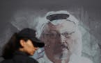FILE - In this Oct. 2, 2019 file photo, a Turkish police officer walks past a picture of slain Saudi journalist Jamal Khashoggi prior to a ceremony, n