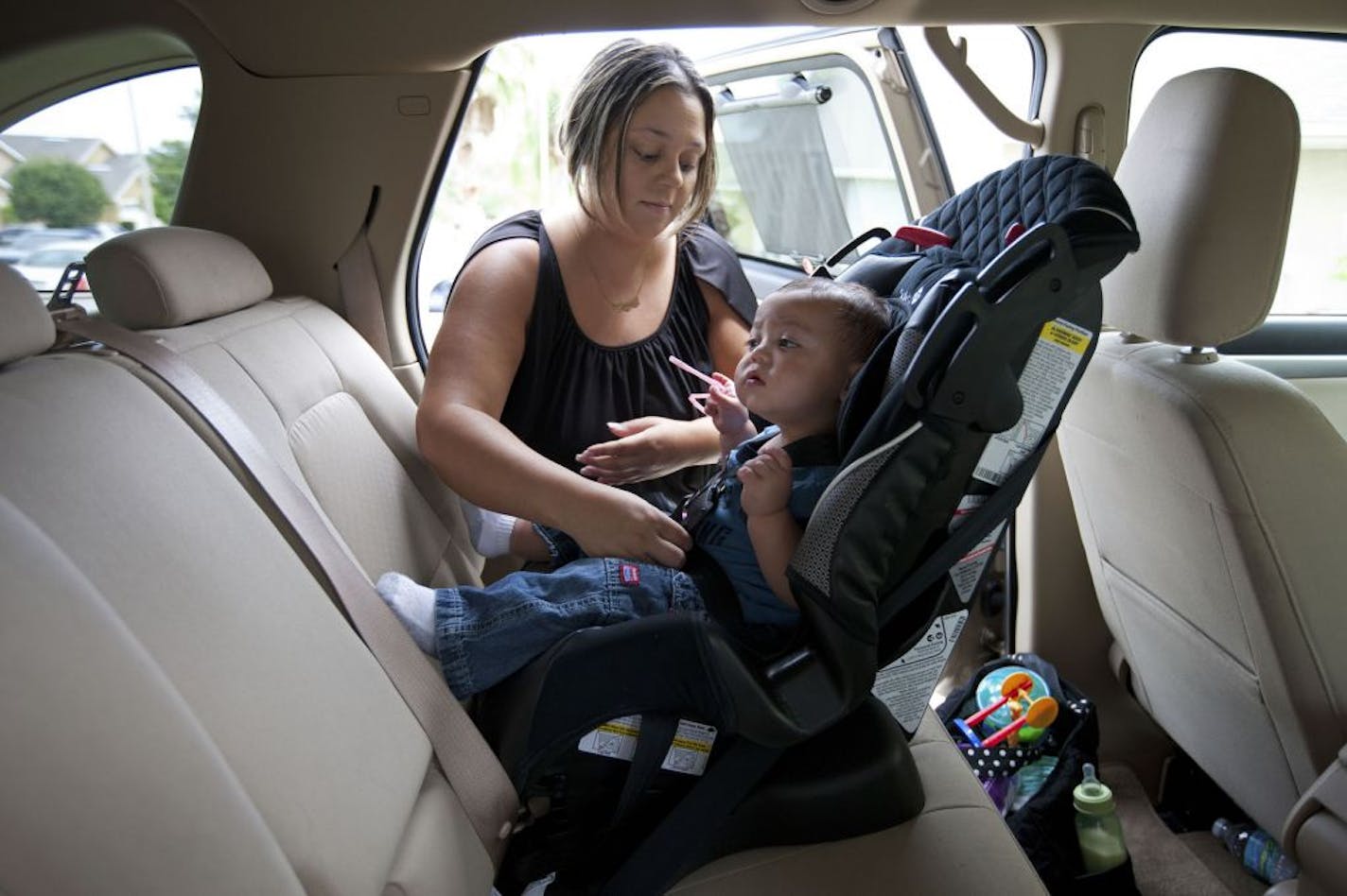 Amanda Cordeiro, a single mother who owes $55,000 in student loans, buckles her nine-month-old son into his car seat, in Groveland, Fla., June 20, 2012. Many borrowers are struggling to pay off their student loans, and the debt collection industry is cashing in.