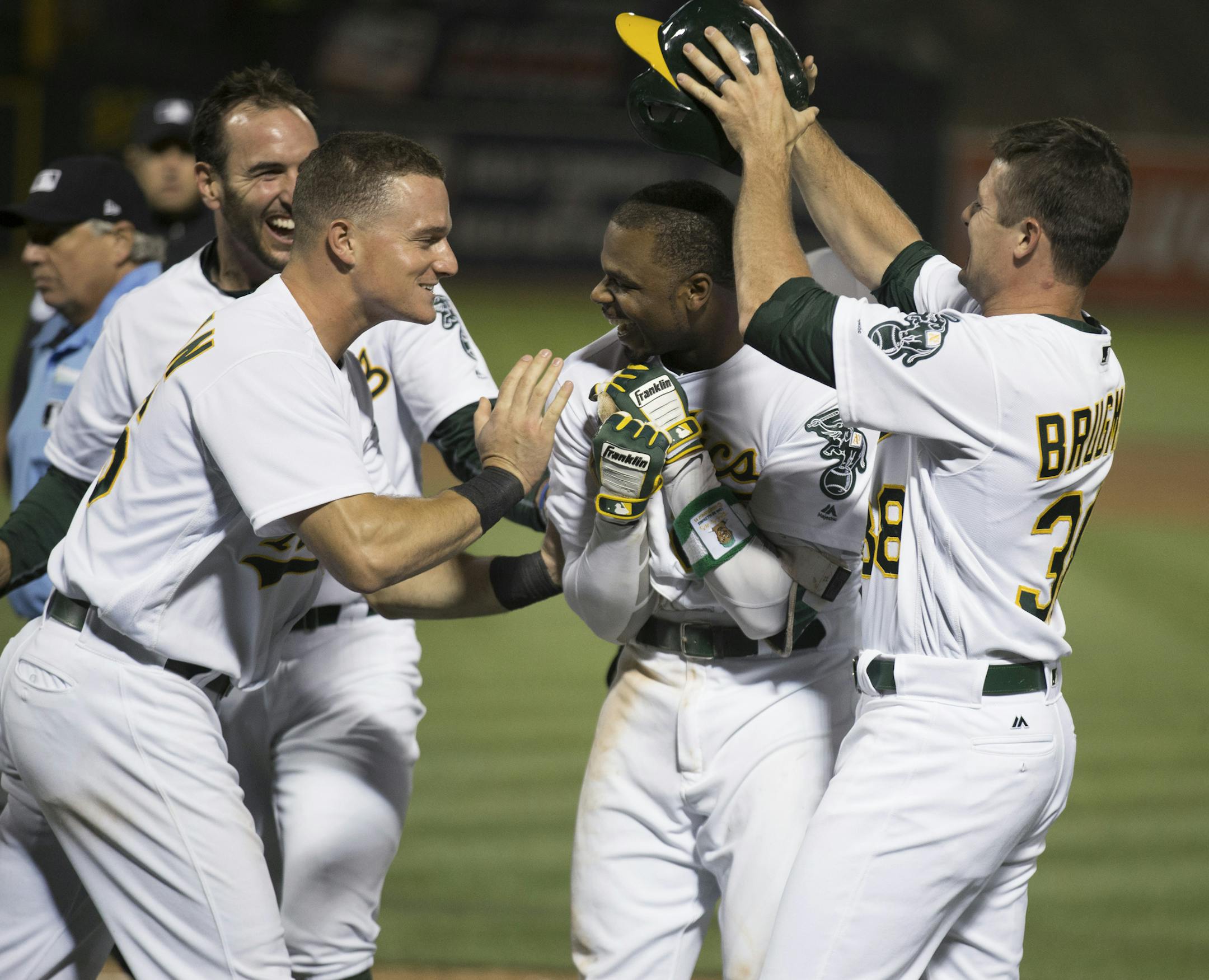 Oakland Athletics' Rajai Davis, center, is greeted by teammates after hitting the game-winning two-run home run during the ninth inning of the team's baseball game against the Minnesota Twins on Saturday, July 29, 2017, in Oakland, Calif. The A's won 5-4. (AP Photo/D. Ross Cameron)