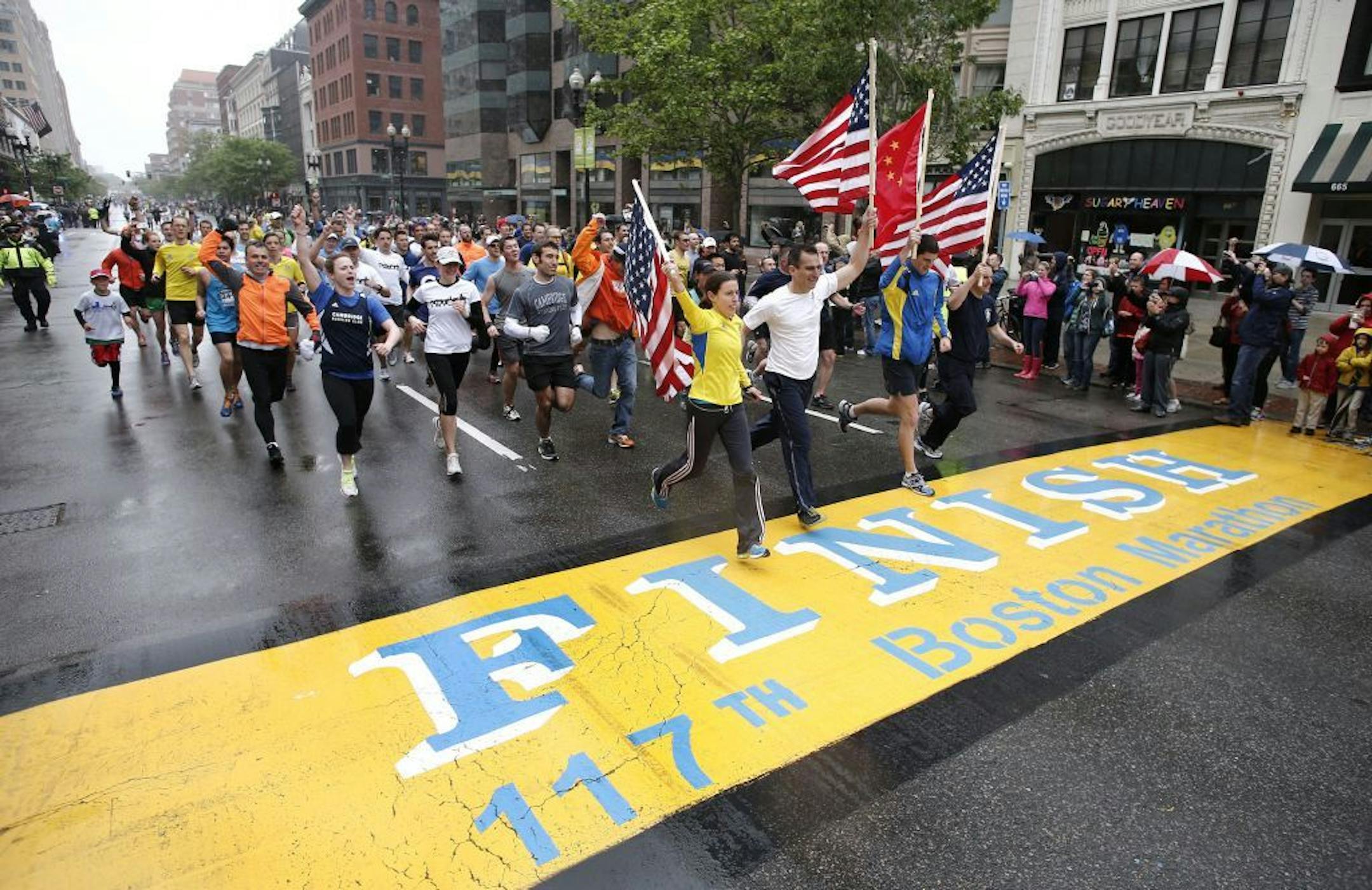 Runners who were unable to finish the Boston Marathon on April 15 because of the bombings cross the finish line on Boylston Street after the city allowed them to finish the last mile of the race in Boston, Saturday, May 25, 2013.