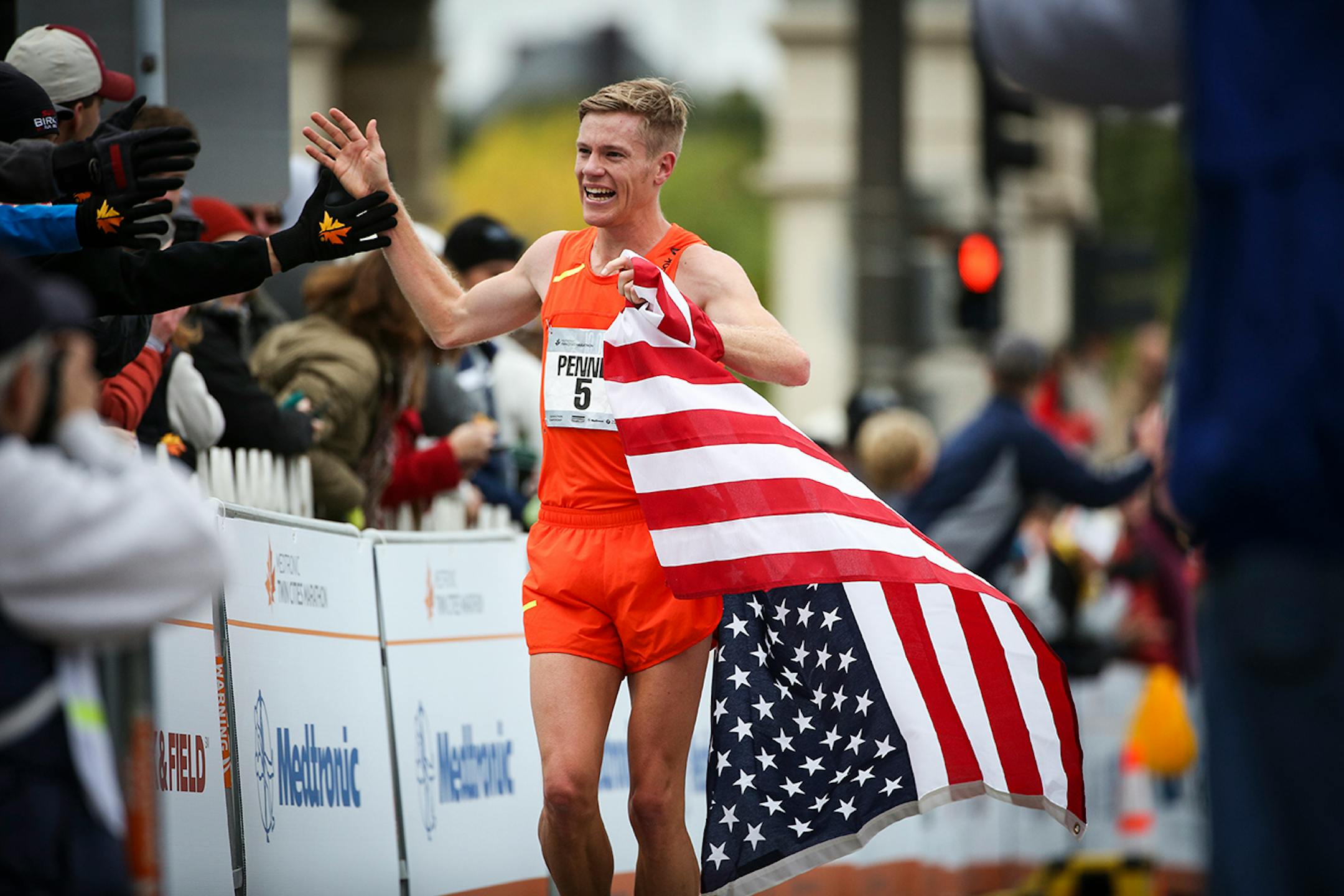 Men's marathon winner Tyler Pennel did his victory lap after he crossed the finish line of the Twin Cities Marathon on Sunday.