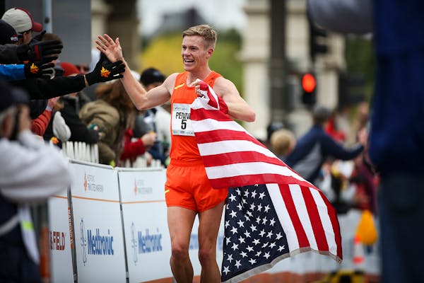 Men's marathon winner Tyler Pennel did his victory lap after he crossed the finish line of the Twin Cities Marathon on Sunday.