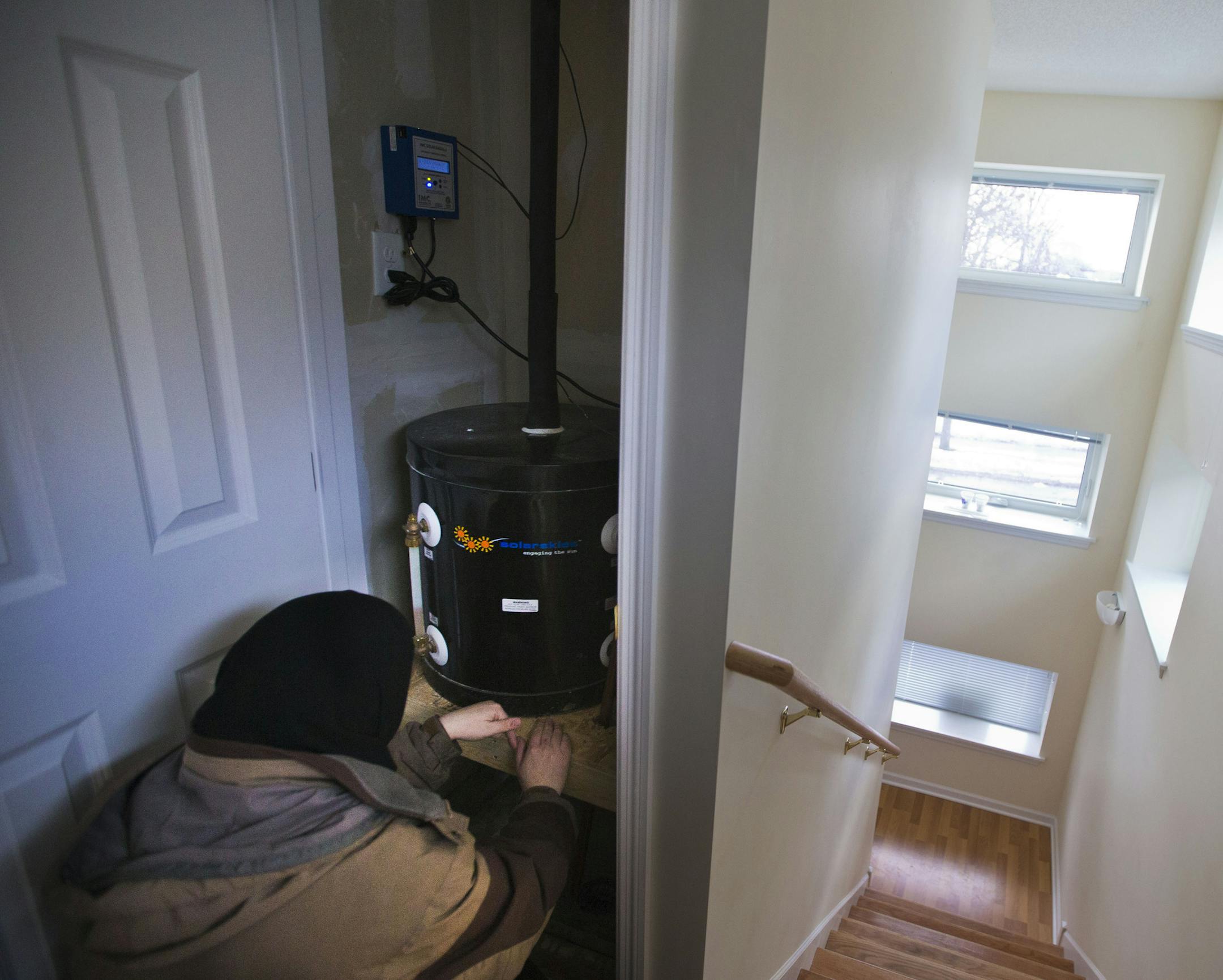 Sarah Olson pointed out the solar drain back tank in a closet of her net zero house in Minneapolis, which has extra thick insulation in the walls and triple-pane glass windows. Thermostats on separate floors also help save energy.