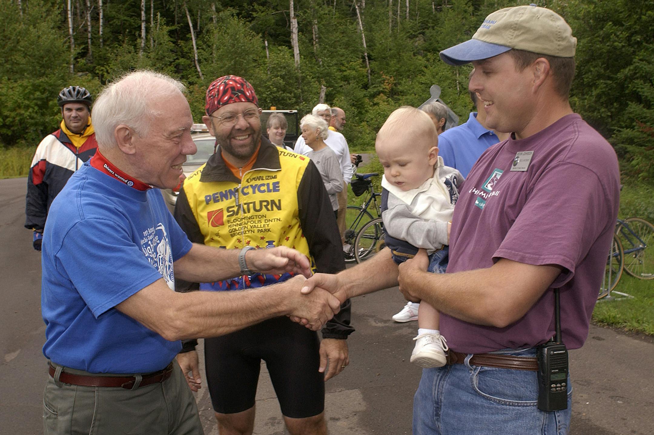 Oberstar is greeted by Kevin Johnson, right, DNR Trail Development Specialist and GGST Trail Coordinator while Gary Sjoquist, center, coordinator of the 50-mile GGST Lighthouse Ride, looks on. Oberstar was on hand for the ride at Split Rock Lighthouse near Silver Bay, MN., on Sat. August 17th, 2002.