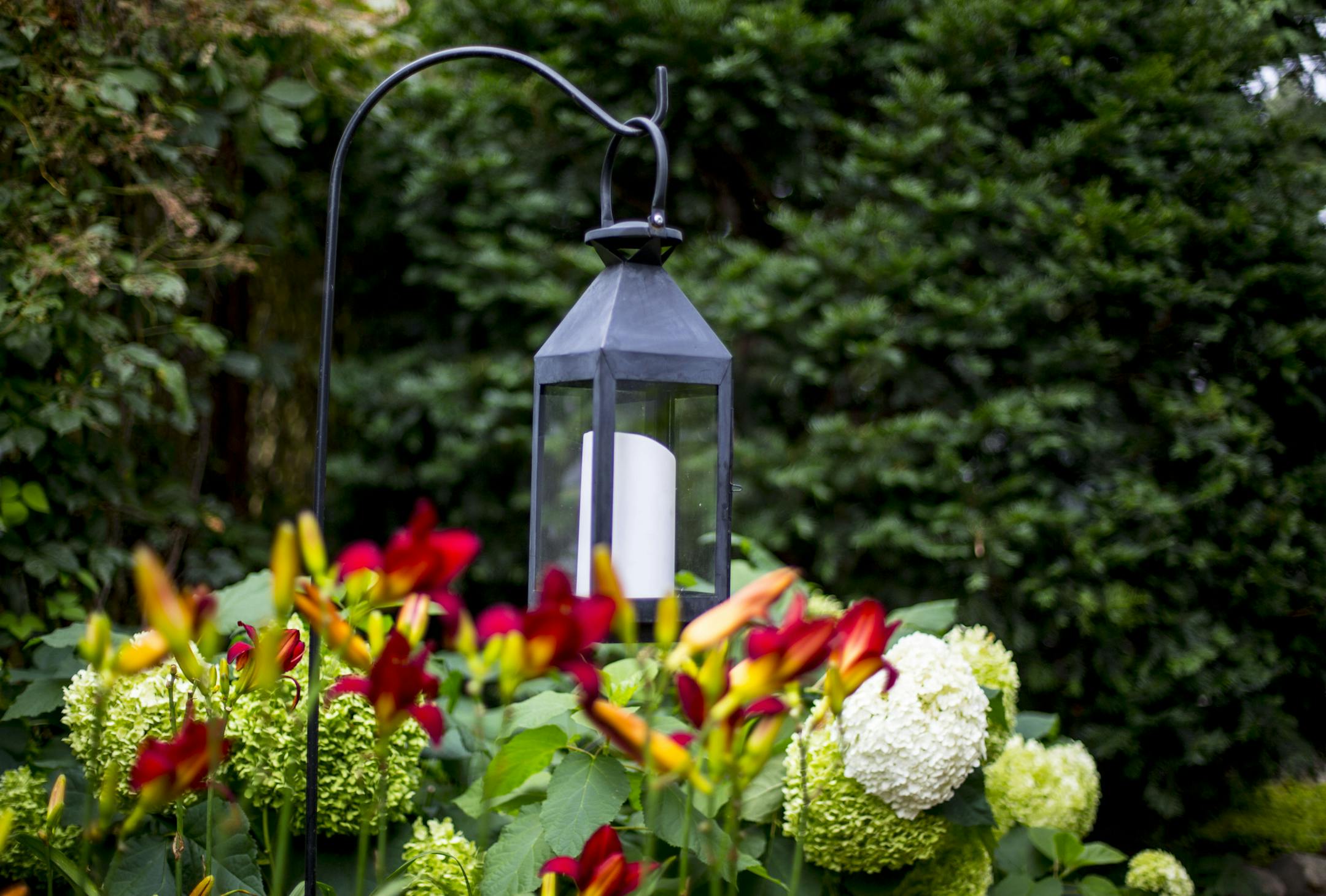 The front pathway towards the backyard features a hanging candle lamp over a bed of flowers. ] ALEX KORMANN • alex.kormann@startribune.com Beautiful Gardens winners Doug Peine and Christine Scotillo have constructed a unique and intricate garden in their small backyard space. The garden features multiple brick and stone pathways surrounding a central pond with a small floating dock with chairs to enjoy the fresh air. There are three other sitting areas around the backyard that is further