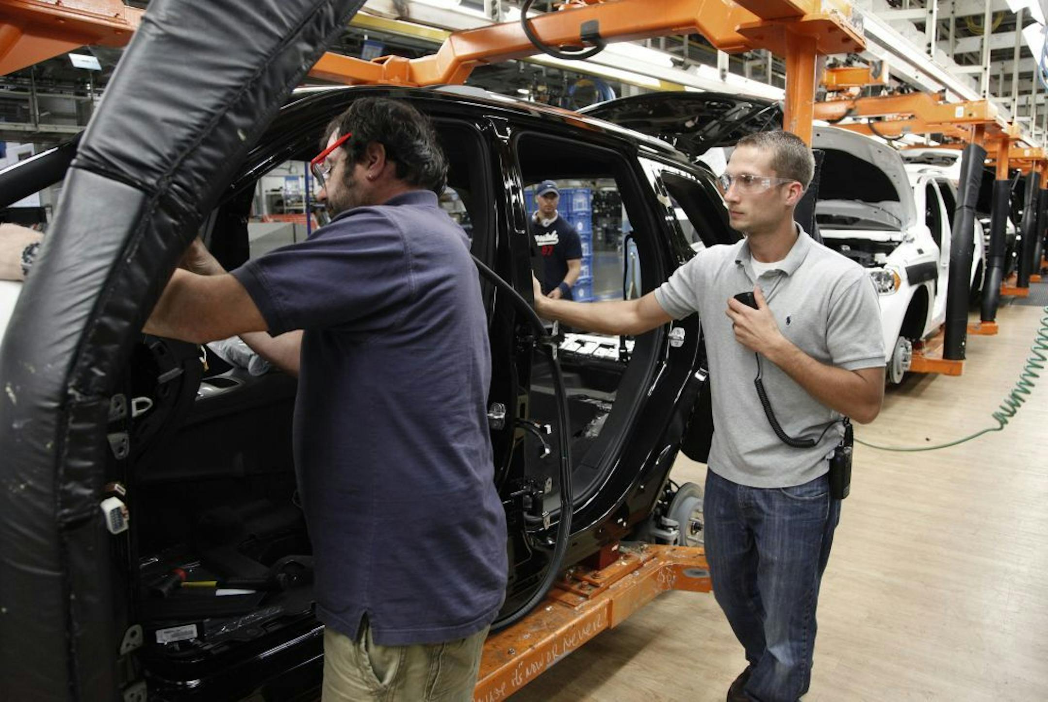 In this Wednesday, May 8, 2013, photo, Jeff Caldwell, 29, right, a chassis assembly line supervisor, watches an assembly at the Chrysler Jefferson North Assembly plant in Detroit. The auto industry is on a hiring spree as car makers and parts suppliers race to find engineers, technicians and factory workers to build the next generation of vehicles.