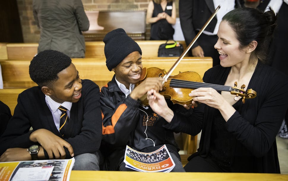 Alexandra Early, a violinist with Minnesota Orchestra, shows Emanual Raseokaja, 16, center, how to play her violin as his schoolmate Bosele Seanego, 1