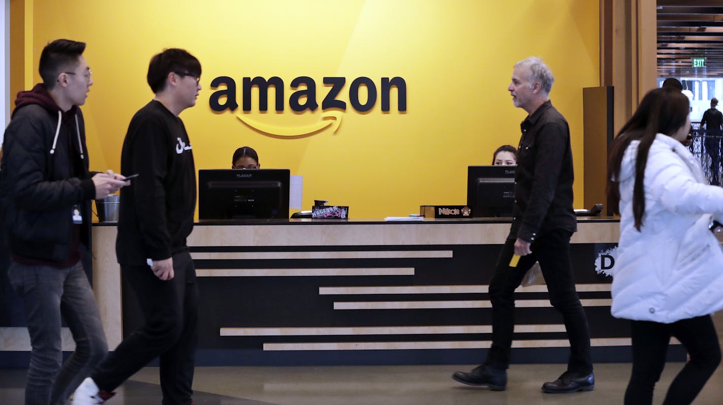 FILE - In this Nov. 13, 2018 file photo, employees walk through a lobby at Amazon's headquarters in Seattle.