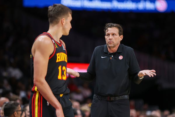 Atlanta Hawks head coach Quin Snyder, right, talks to guard Bogdan Bogdanovic, left, in the first half of an NBA basketball game against the Minnesota