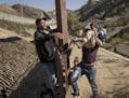 A man holds a Mexican migrant child as he jumps the border fence to get into the U.S. side to San Diego, Calif., from Tijuana, Mexico, Saturday, Dec. 