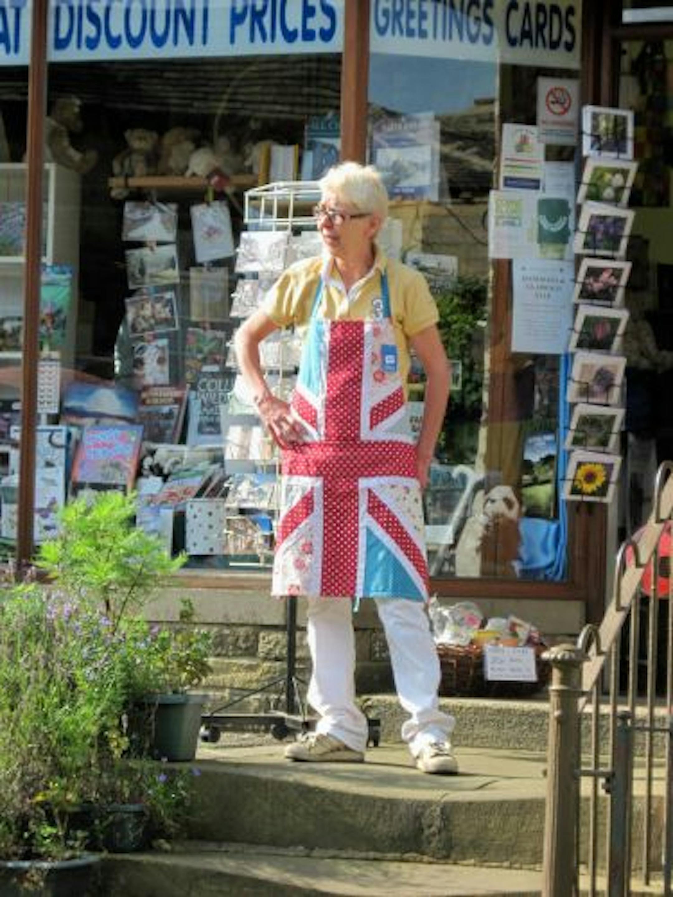 A shopkeeper shows off her Union Jack apron on Main Street in the village of Haworth.