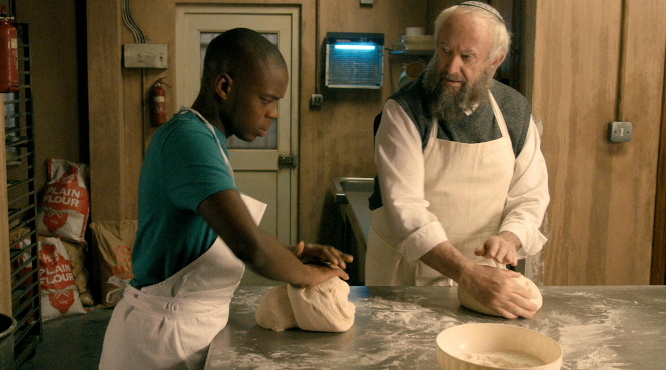 Jerome Holder and Jonathan Pryce in "Dough."