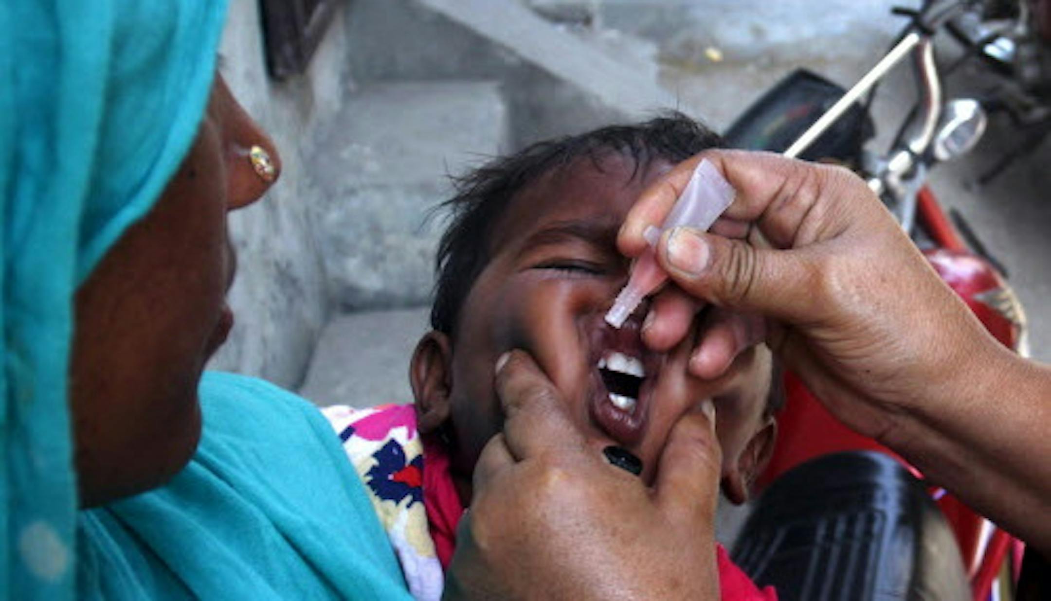 A Pakistani health worker gives a child a polio vaccine in Lahore, Pakistan, Monday, May 5, 2014. For the first time, the World Health Organization on Monday declared the spread of polio an international public health emergency that could grow in the next few months and unravel the nearly three-decade effort to eradicate the crippling disease. (AP Photo/K.M. Chaudary)