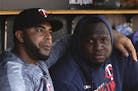 Minnesota Twins' Nelson Cruz, left, and Miguel Sano talk in the dugout in the fourth inning of a baseball game against the Detroit Tigers in Detroit, 