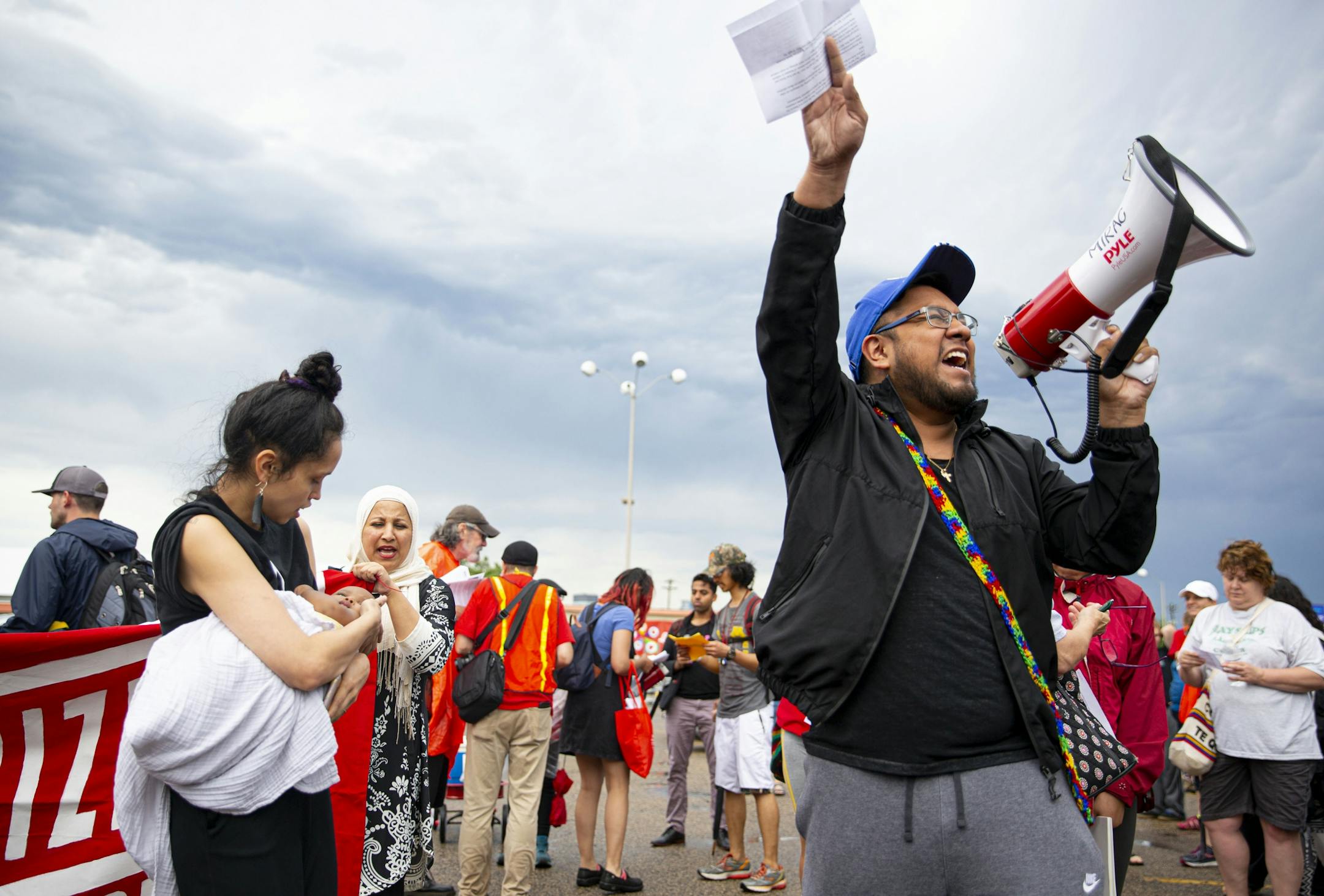 Mixie Bing (left) holds her daughter, Zoh, while Victor Ramirez (right) leads the crowd in a chant. ALEX KORMANN ¥ alex.kormann@startribune.com Approximately 1,000 people marched through the streets of Minneapolis on Sunday June 30, 2019 protesting the treatment of migrants on the U.S. border. "Stop separating families, close the camps," said Mari Mansfield, an organizer for the event.