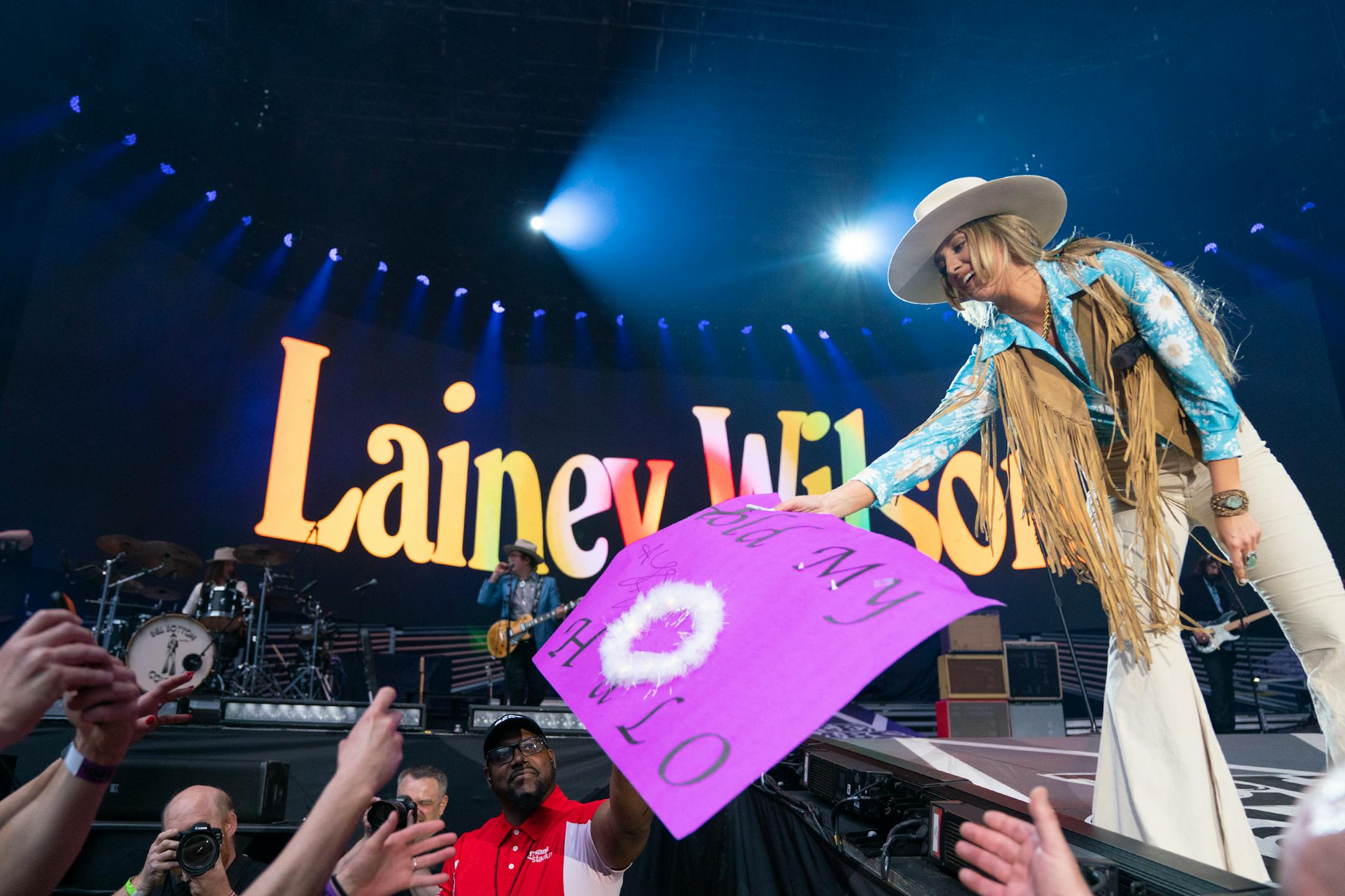 Lainey Wilson hands a sign back to a fan after signing it on stage while opening for Luke Combs at U.S. Bank Stadium.