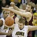 Iowa guard Mike Gesell, bottom, fights for a loose ball with Minnesota center Elliott Eliason, top right, during the first half of an NCAA college bas