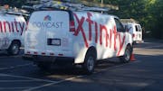 FILE - In this Sept. 17, 2015, file photo, Comcast trucks are parked in a lot in the company's Westford, Mass. operations center.