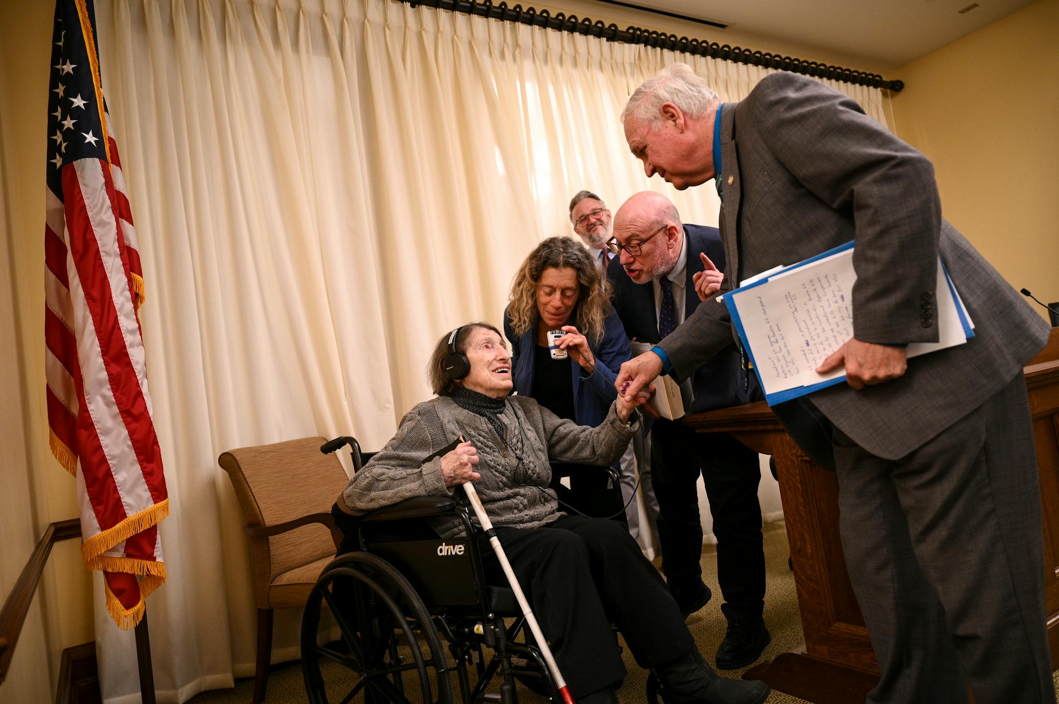 Minnesota Rep. Dean Urdahl (R-Grove City) leans in to shake hands with Dora Zaidenweber after a bill she testified in support of advanced to the education finance committee Wednesday, March 15, 2023 at the Minnesota State Capitol in St. Paul, Minn. Rep. Frank Hornstein (DFL-Minneapolis), right of center, introduced Urdahl to Zaidenweber as a "real mensch".  Zaidenweber, a 99-year-old Holocaust survivor, testified in support of a bill to require schools to offer Holocaust and genocide education in the middle and high school social studies curriculum.