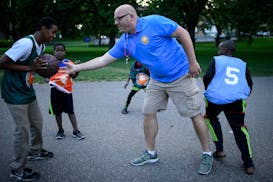 Ryan Sayre of the St. Cloud Police Department plays basketball with kids from the south-side neighborhood at the Community OutPost in June 2018. The c