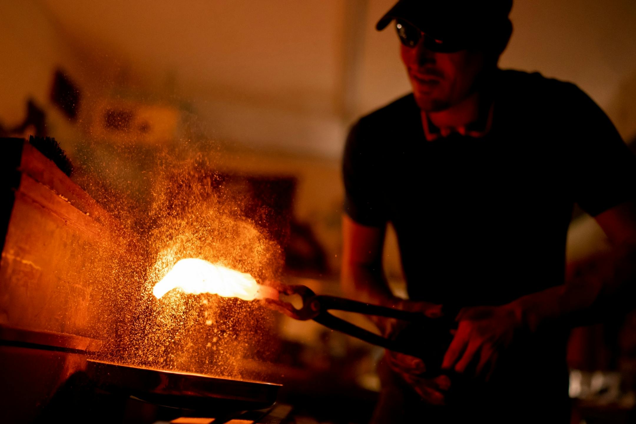 Jason Kraus heated a length of steel cable to 2200 degrees to begin the process of turning it into a knife blade. Here he doused it with borax powder to minimize oxidation.