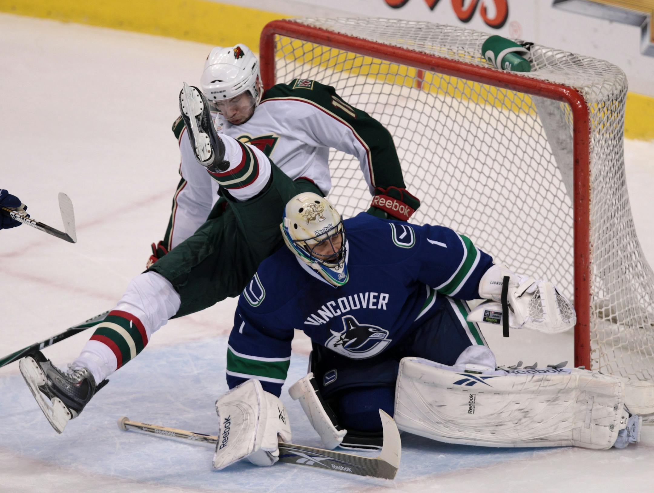 Minnesota Wild's Colton Gillies, left, falls on top of Vancouver Canucks' Roberto Luongo during the first period of an NHL hockey game in Vancouver, British Columbia on Thursday April 7, 2011. (AP Photo/The Canadian Press, Darryl Dyck)